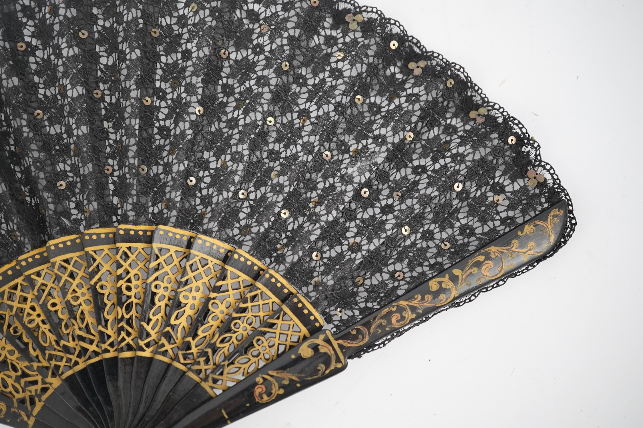 Three novelty fans with a mixed Brussels lace fan and black lace fan, a small language of love in flowers fan, a paper windmill advertising French Café fan, a carved cream Bakelite fan, a black and gilt, lace and sequin